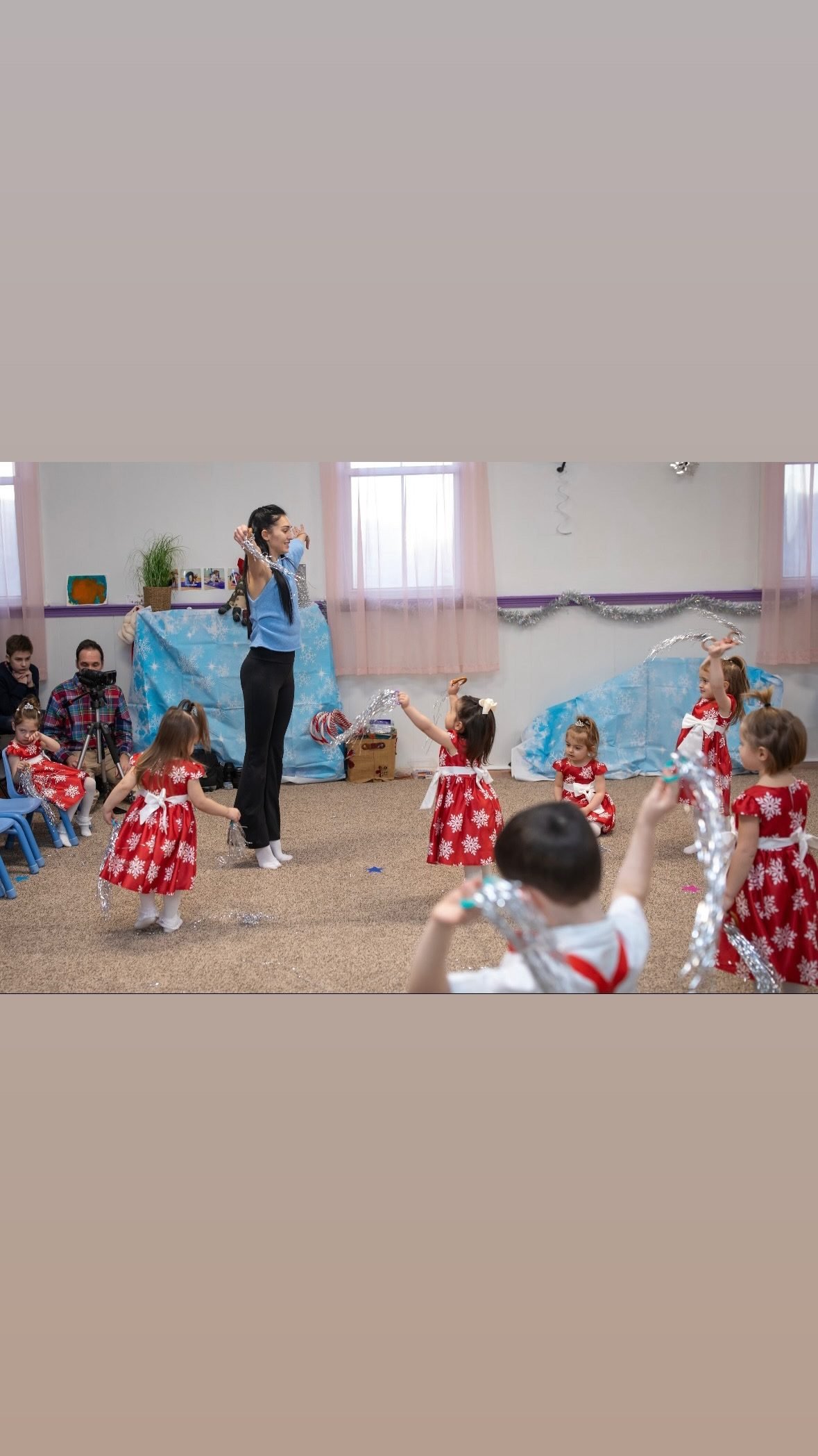 Coach leading toddlers in a dance with silver streamers