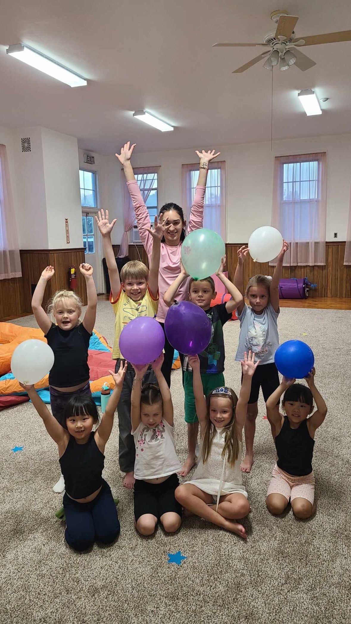 Coach and campers holding balloons with their arms raised