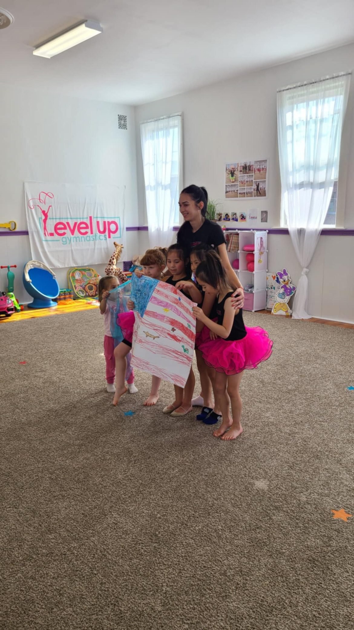 Coach with a group of young gymnasts holding up a drawing in the Level Up gym