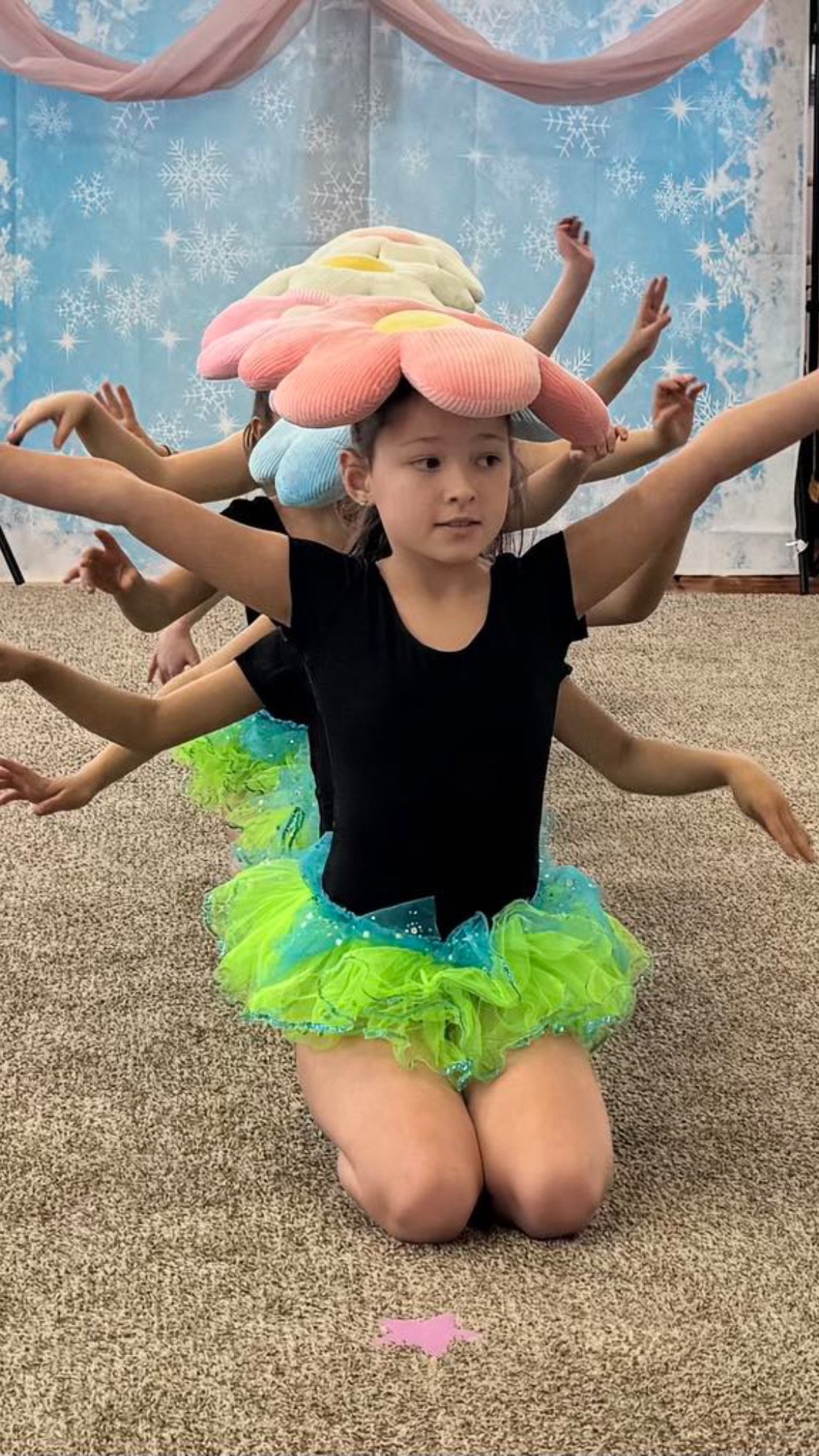 Girls performing a dance in flower hats and bright tutus