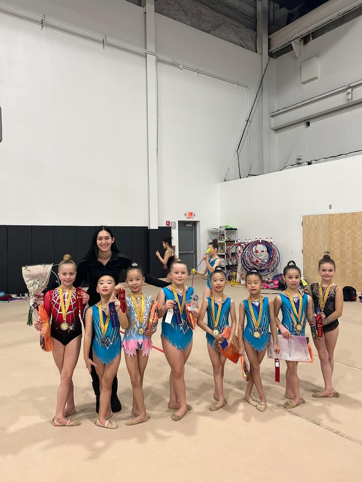 Level Up Gymnastics coach with her gymnasts wearing medals